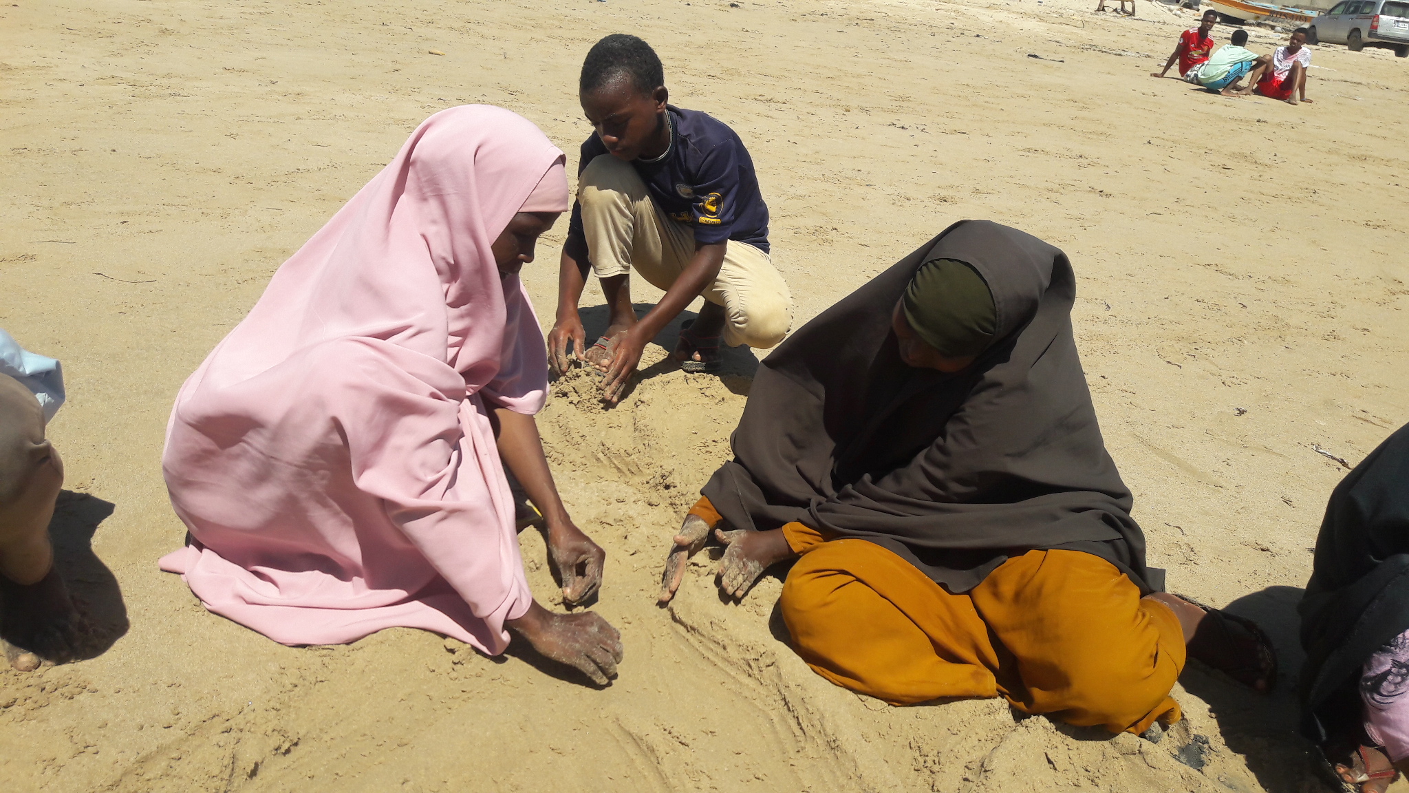 people making shapes in the sand