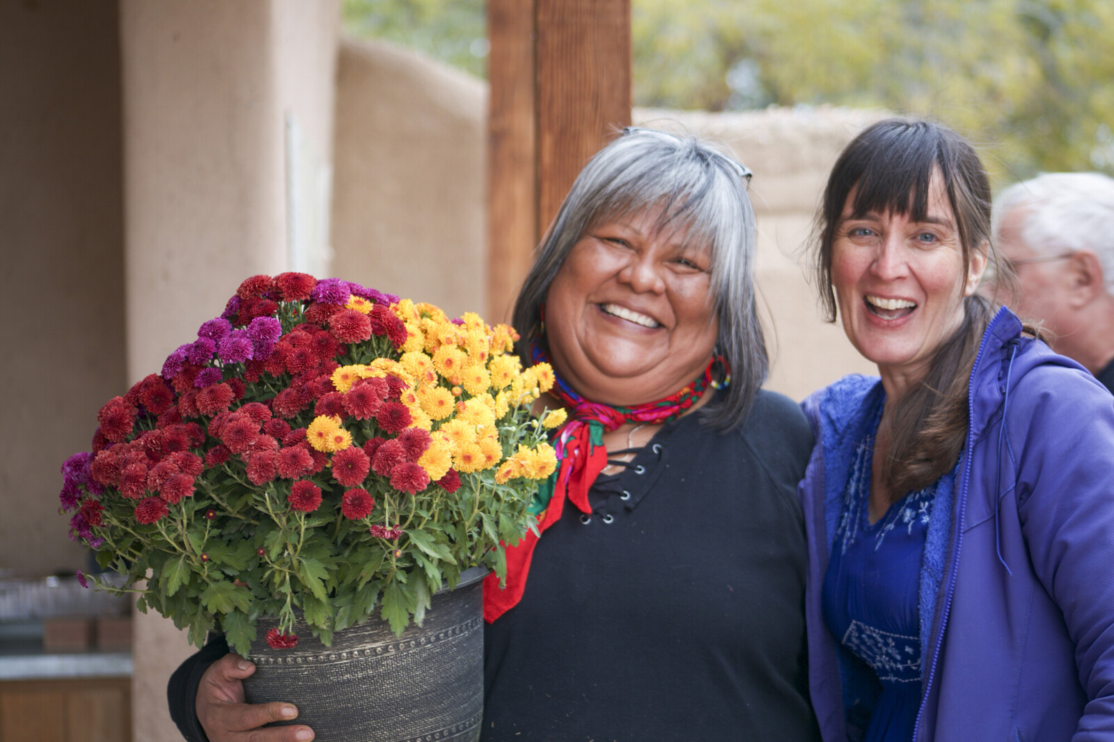 Two women smiling together with one holding a flower pot