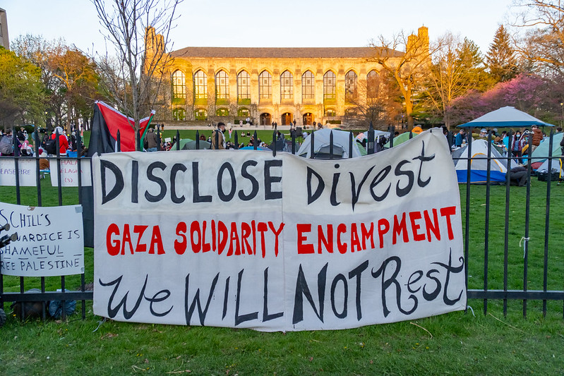 Sign on fence in front of a lawn that says Disclose Divest Gaza solidarity encampment