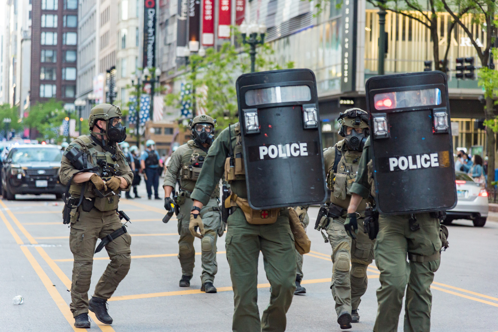 a group of five police offices wearing tactical gear and carrying shields walking down Michigan avenue in Chicago