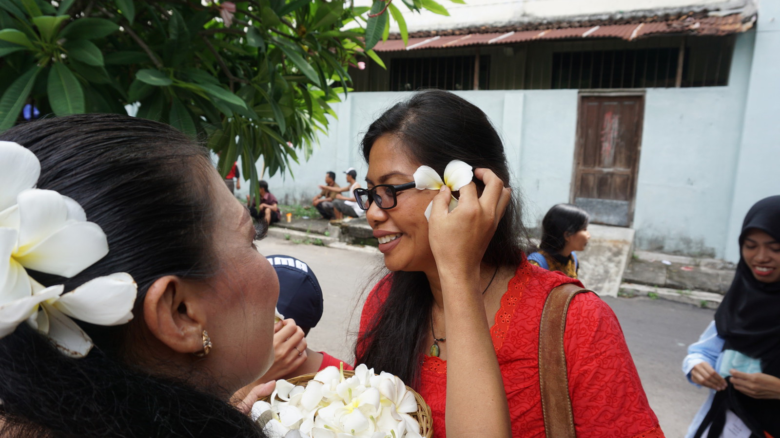 person putting flowers behind a person's ear