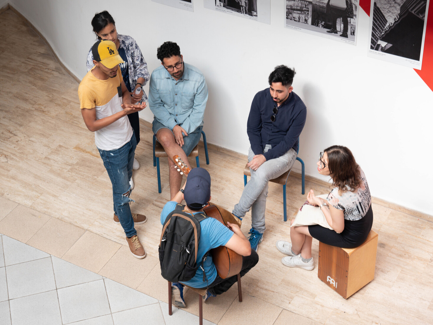 people seated in a circle in discussion, one sits down and plays guitar