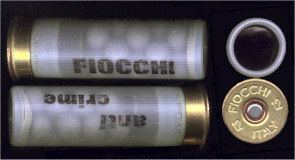 Photo of an example of a multi-munition. It is a translucent plastic cylindrical cartridge, and the shadowy outlines of rubber buckshot inside are visible. The cartridge is branded 