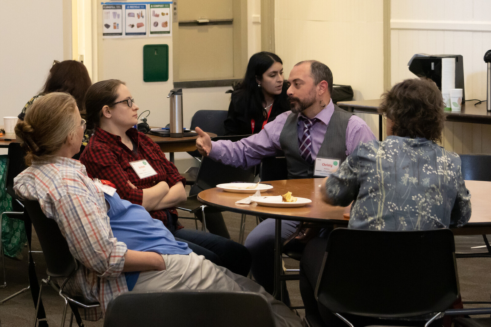 A group of four people sit together around a table talking.