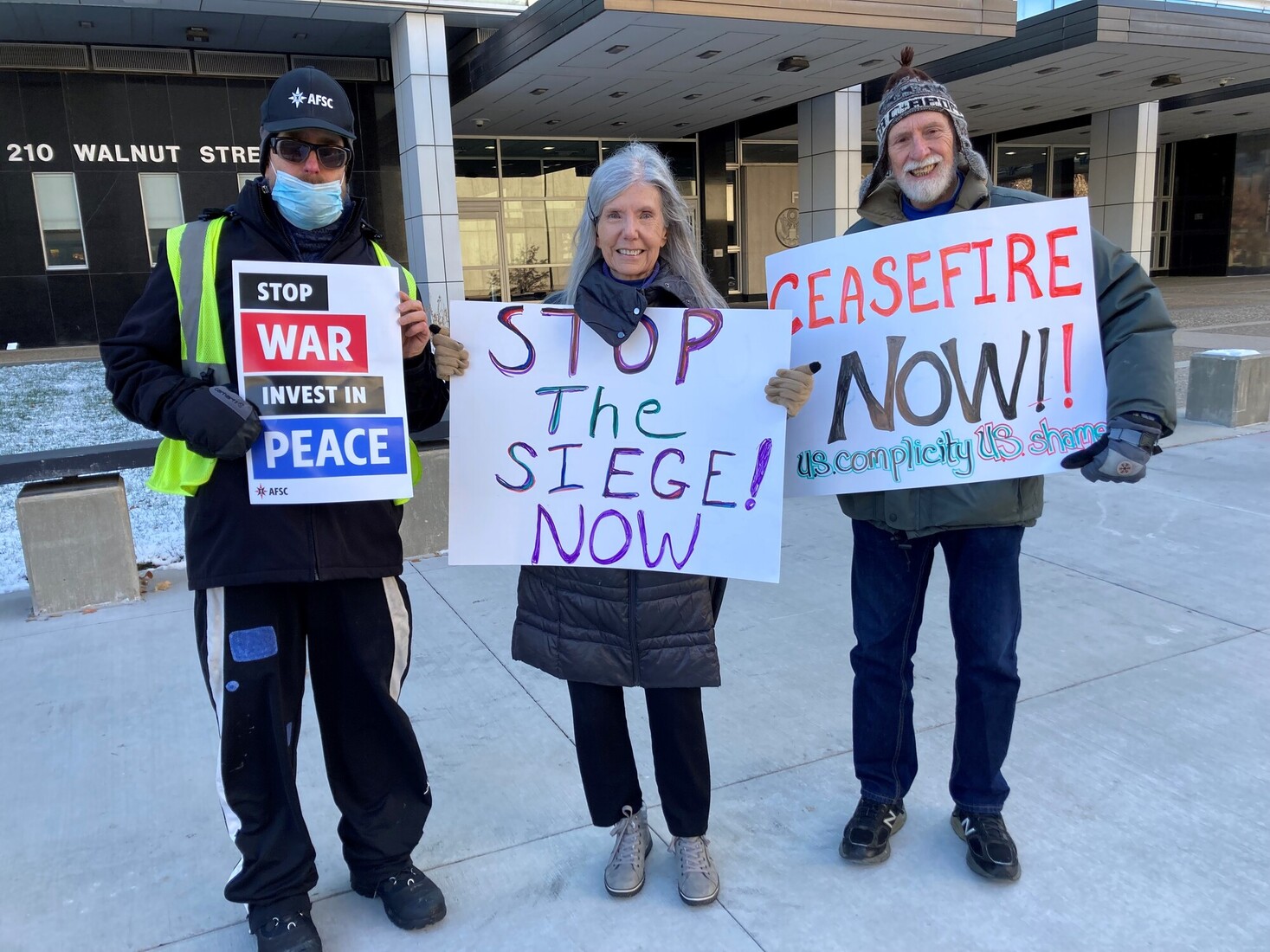 3 people stand with posterboard signs to end the war in Gaza