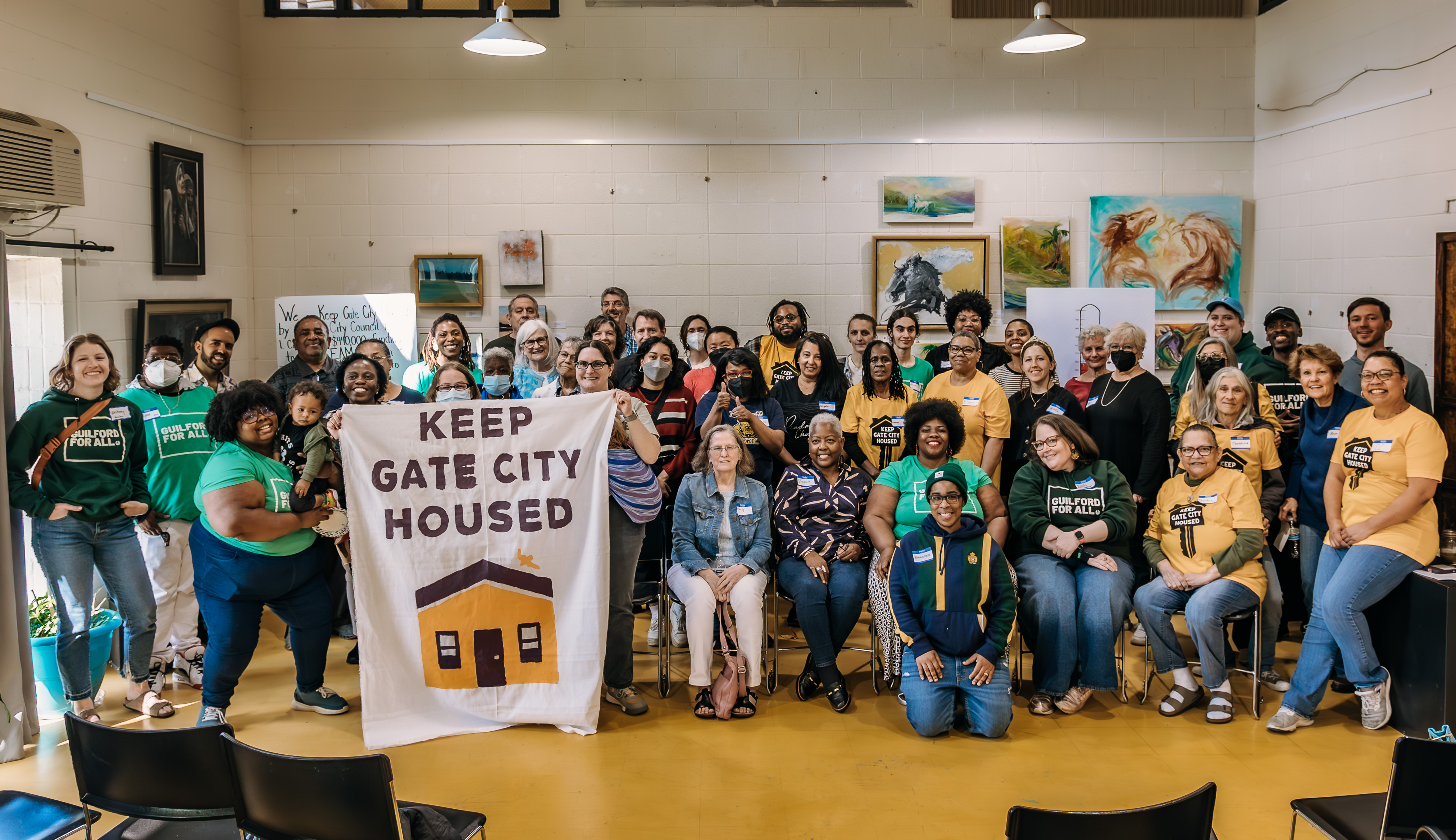 Image of a group of community members with a sign and shirts that read 'Keep Gate City Housed'