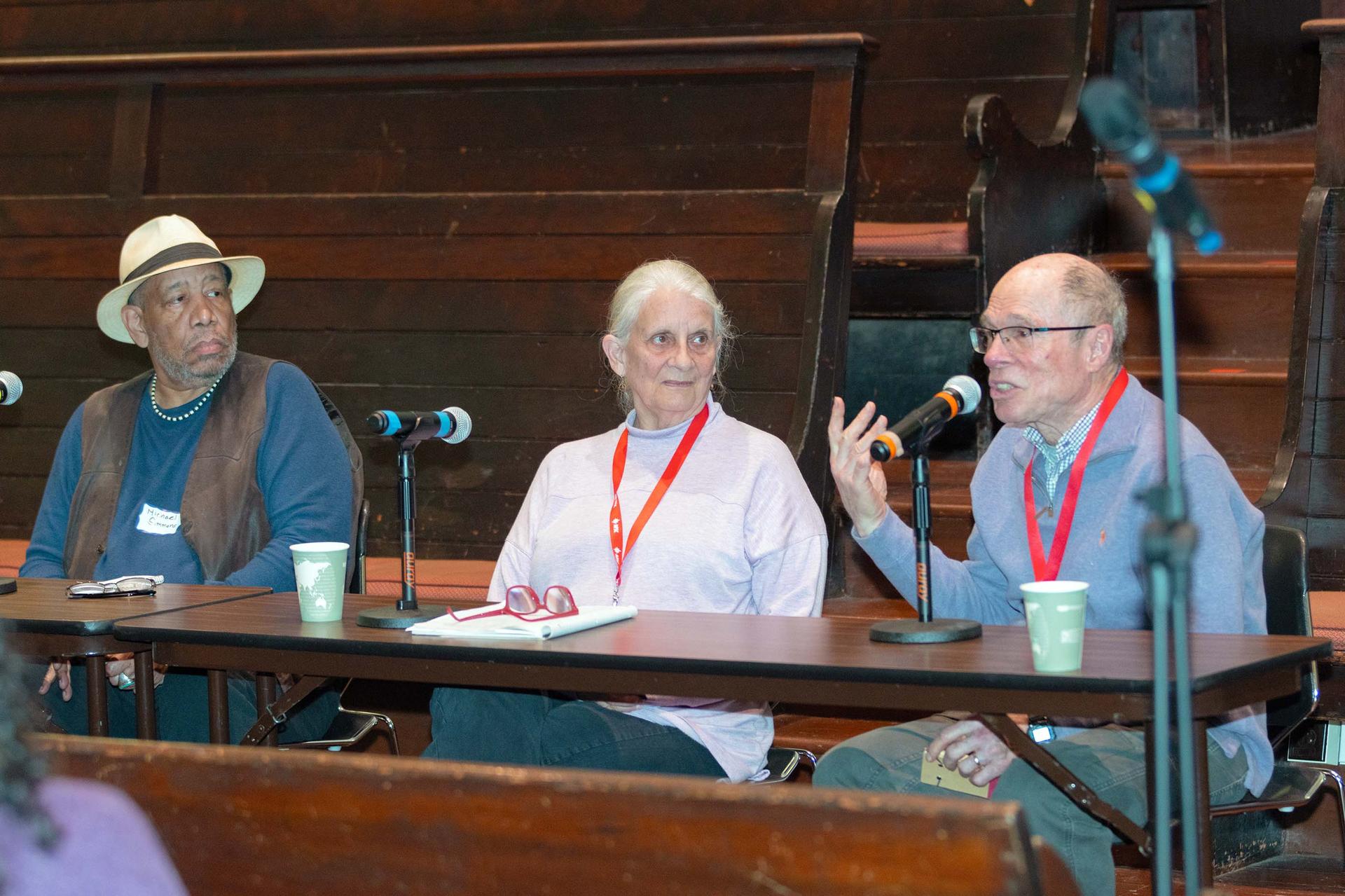 Three people sit at a table addressing an audience.