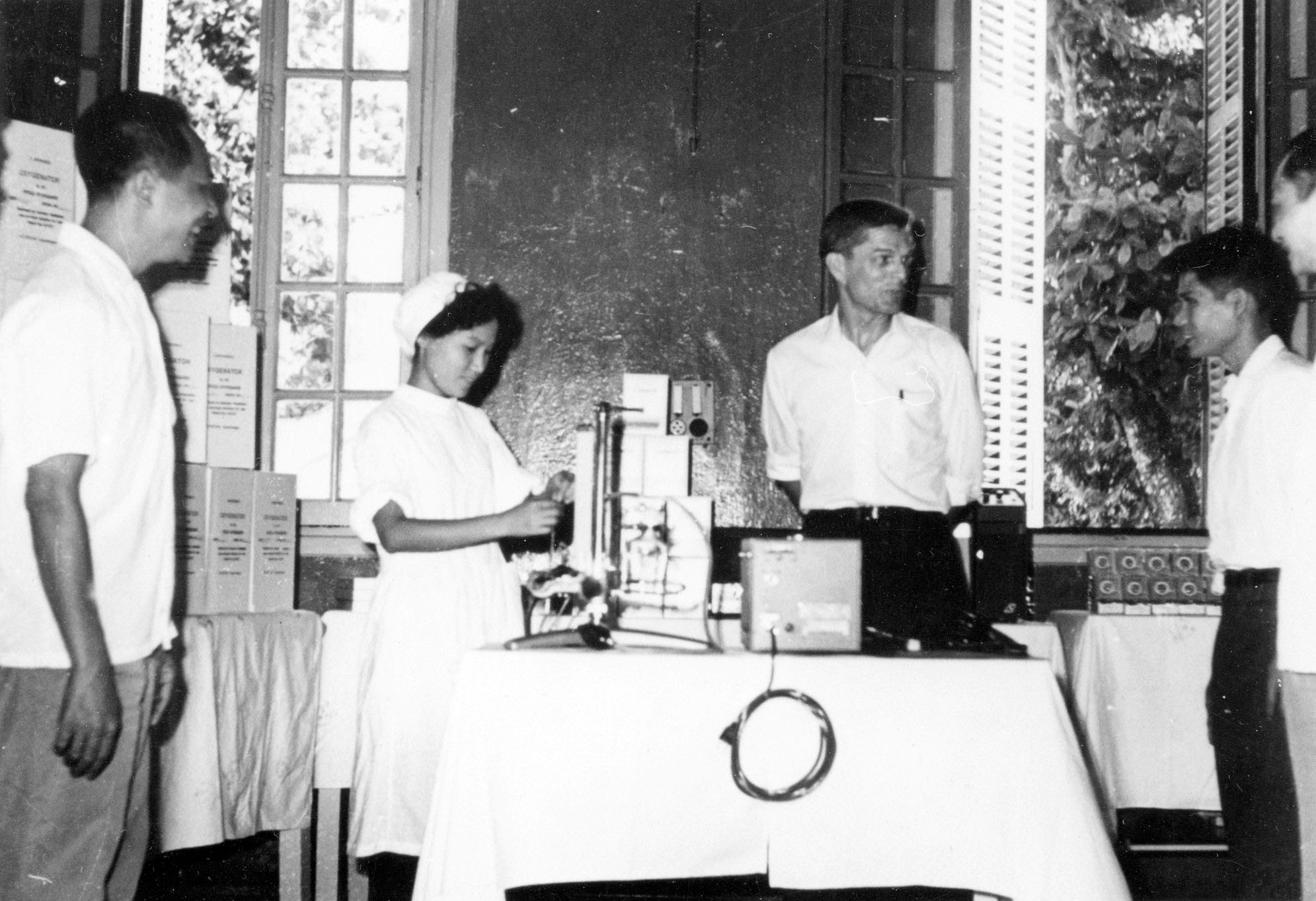 Four people standing around a table with medical equipment