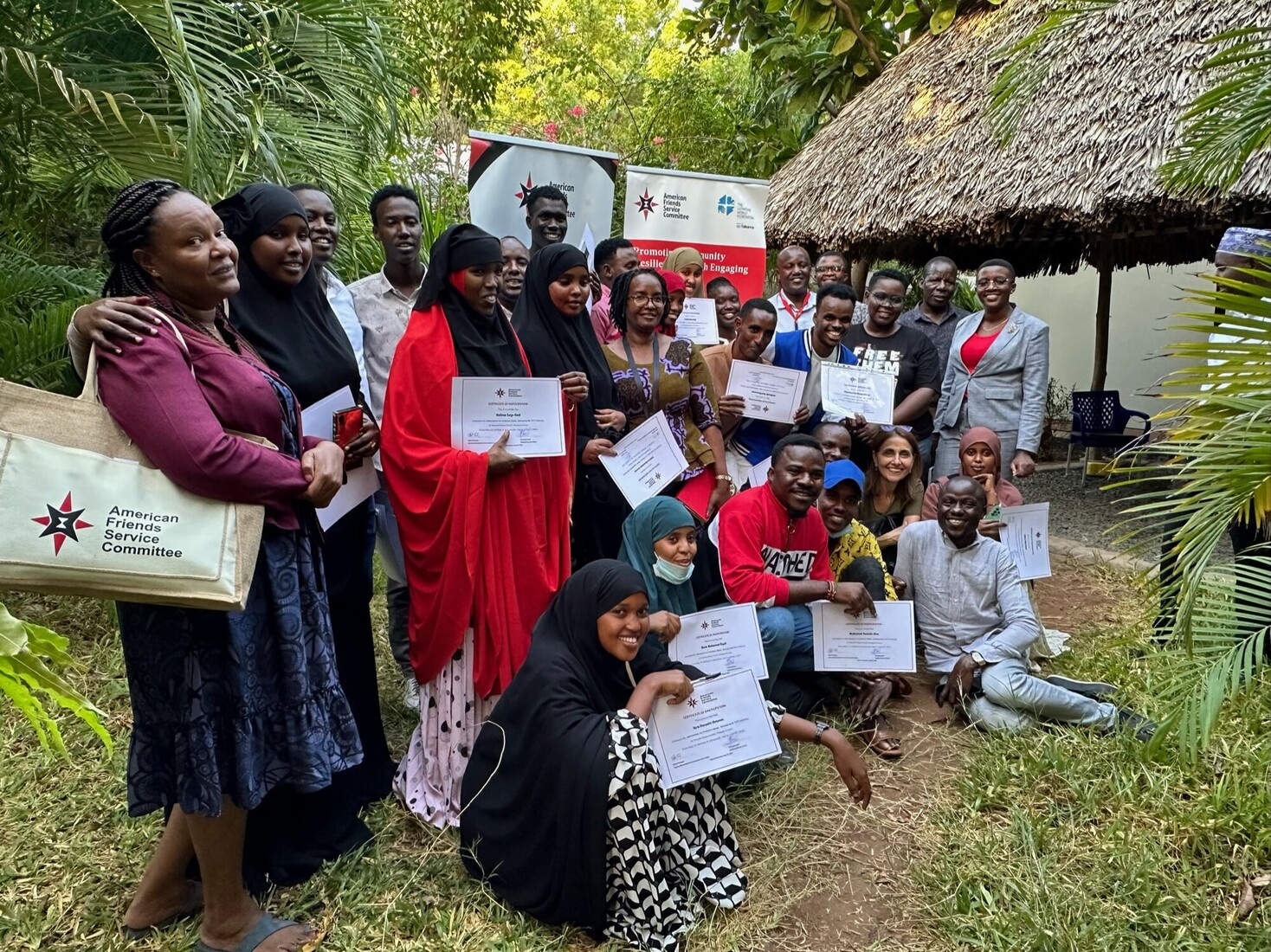 A group of people stand and sit in rows, holding certificates