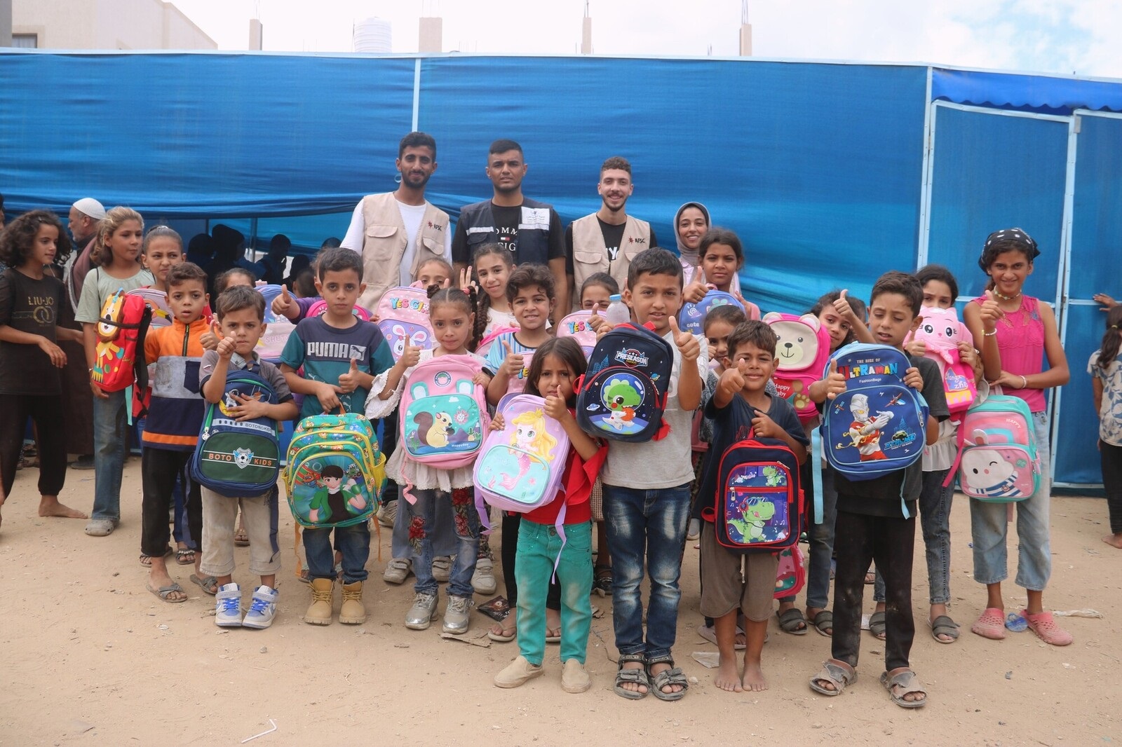 Group of children hold backpacks