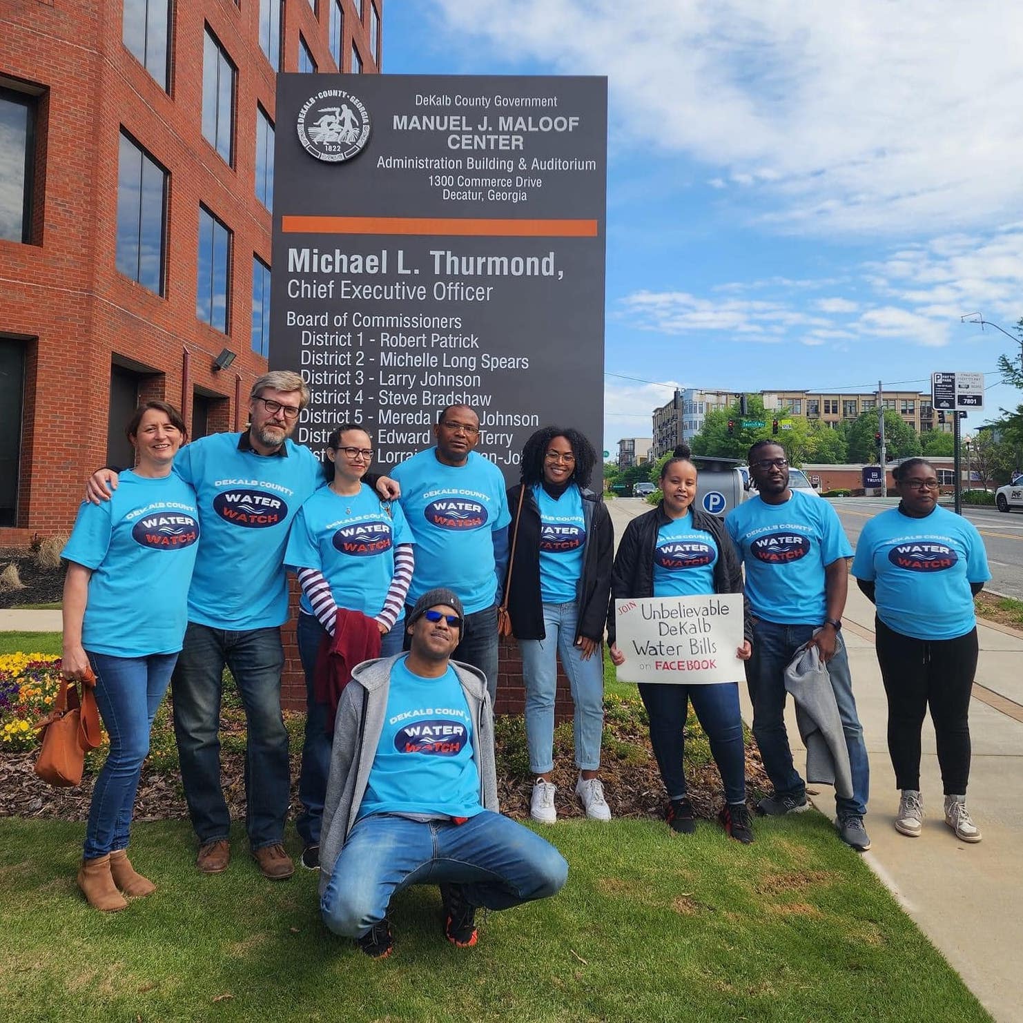 Image of a group wearing 'DeKalb Water Watch' shirts in front of an administration building