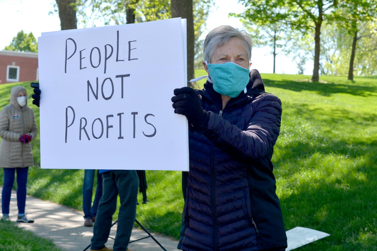 Person holding a "People not Profits" sign 
