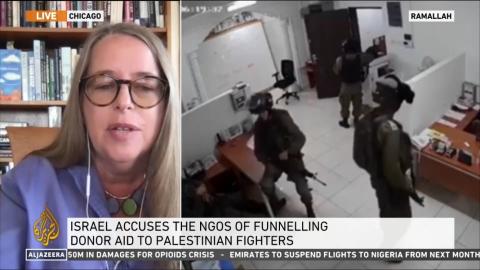 Woman speaking on a news program with footage of an Israeli raid