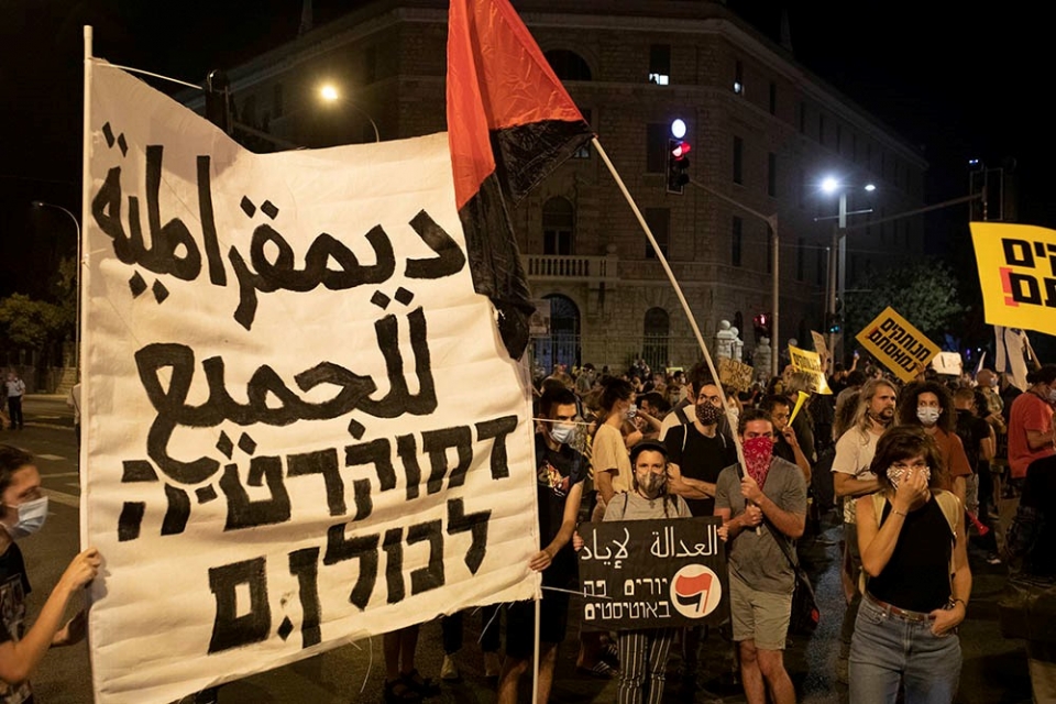 Protesters holding a "Democracy for all" sign in Arabic and Hebrew