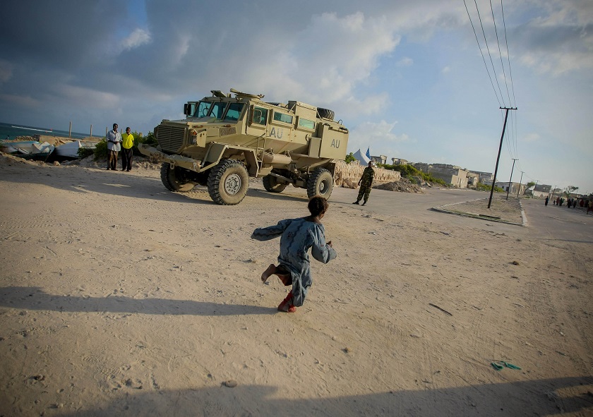 A young Somali girl runs in front of an African Union Mission in Somali (AMISOM) armed personnel carrier, Lido Beach in the Kaaraan District of Mogadishu, Somalia (United Nations Phot/Creative Commons)