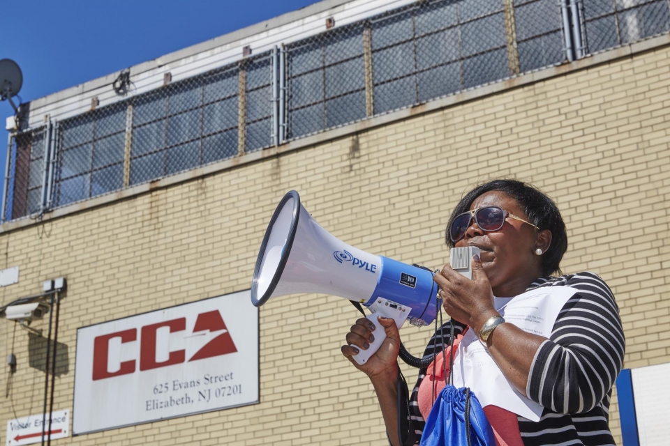 Woman speaks into a megaphone in front of a for-profit prison in Elizabeth, New Jersey.